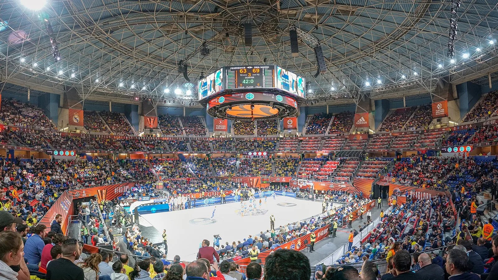 Archive basketball game at Fernando Buesa Arena, illustrative of NBA-EuroLeague talks, not a photo of the negotiations. Vanbasten 23 / Wikimedia Commons, CC BY-SA 4.0 (https://creativecommons.org/licenses/by-sa/4.0/); cropped to 16:9. Original: https://commons.wikimedia.org/wiki/File:Panor%C3%A1mica_del_Fernando_Buesa_Arena.jpg
