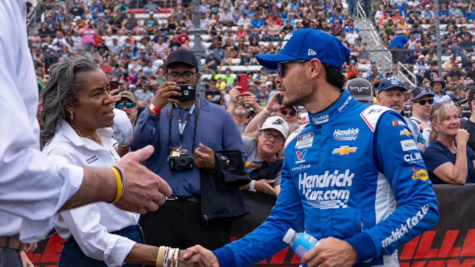 Кайл Ларсън на пистата в Мартинсвил през 2025 г. — архивна снимка, не от победата в Канзас през 2026 г.; Virginia Office of the Governor, CC BY 4.0 (https://creativecommons.org/licenses/by/4.0/); оригинал: https://commons.wikimedia.org/wiki/File:Cook_Out_400_NASCAR_Cup_Series_Race,_Martinsville_3-30-25_(120).jpg; изрязана и оразмерена до 16:9.