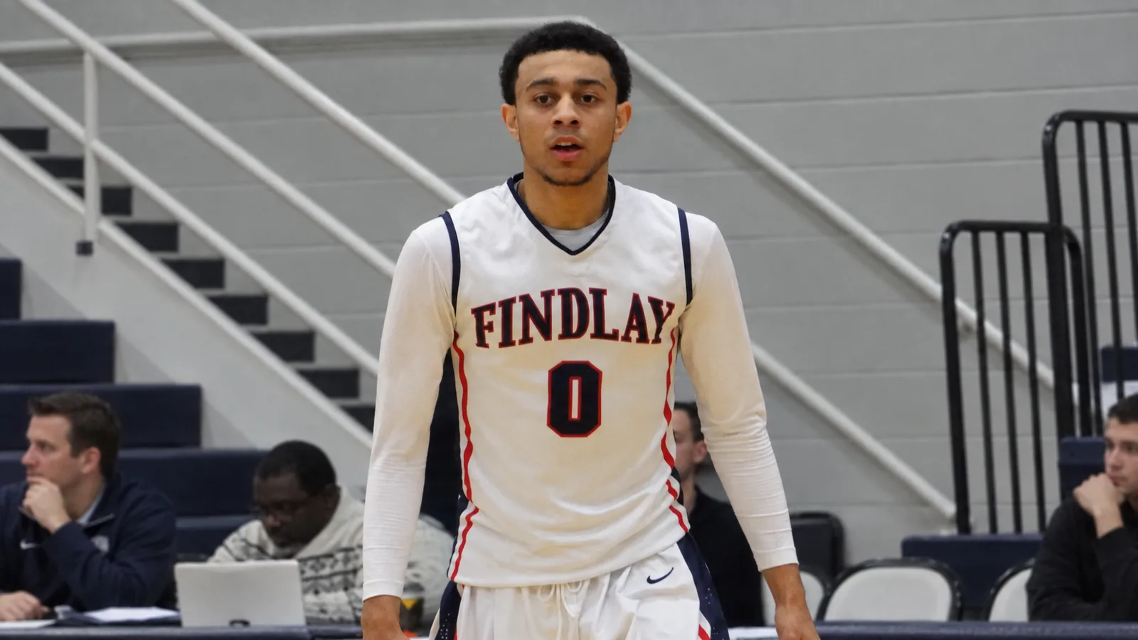 Найджъл Уилямс-Гос в архивен кадър от 2012 г. с екип на Findlay Prep; AI редакционна преработка с разширен фон. Изходна снимка: Bryan Horowitz, CC BY-SA 2.0 (https://creativecommons.org/licenses/by-sa/2.0/), https://commons.wikimedia.org/wiki/File:Nigel_Williams-Goss.jpg.