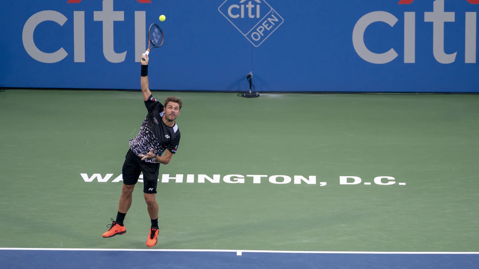 Архив: Стан Вавринка на Citi Open, 31 юли 2018 г.; не е кадър от Базел 2026. Keith Allison / Wikimedia Commons, CC BY-SA 2.0. https://commons.wikimedia.org/wiki/File:Stan_Wawrinka_(43058853114).jpg ; https://creativecommons.org/licenses/by-sa/2.0/ ; изрязано и преоразмерено до 16:9 без AI редакция; адаптация под същия лиценз.