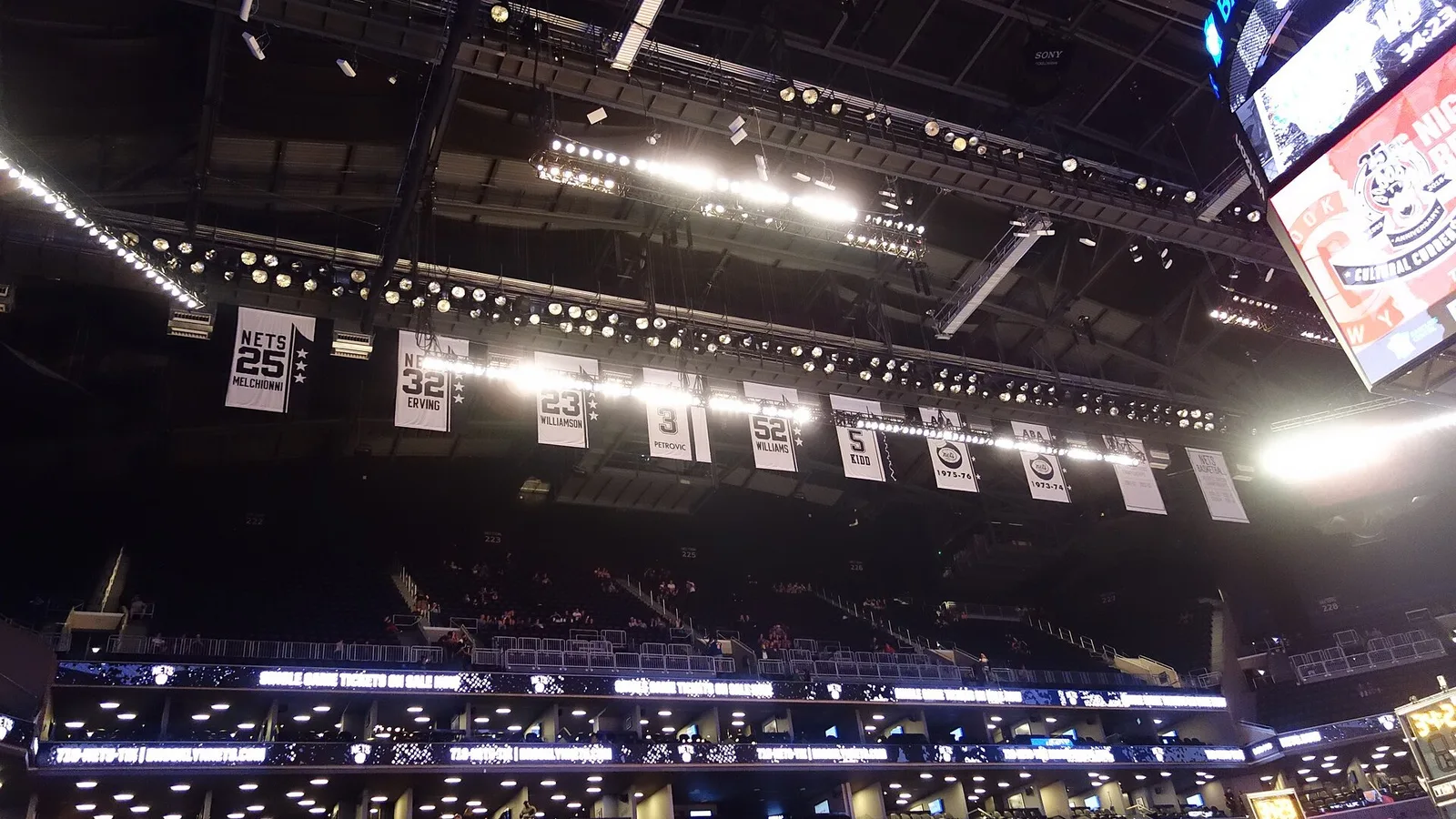 Архив: почетните номера и шампионските банери на Нетс от АБА в Barclays Center, 3 октомври 2018 г.; илюстрира историческото наследство, не показва новите екипи за 2026/27. Tdorante10 / Wikimedia Commons, CC BY-SA 4.0; изрязано до 16:9. Оригинал: https://commons.wikimedia.org/wiki/File:Brooklyn_Nets_vs_NY_Knicks_2018-10-03_td_13_-_Pregame.jpg ; лиценз: https://creativecommons.org/licenses/by-sa/4.0/ ; адаптацията е под CC BY-SA 4.0.