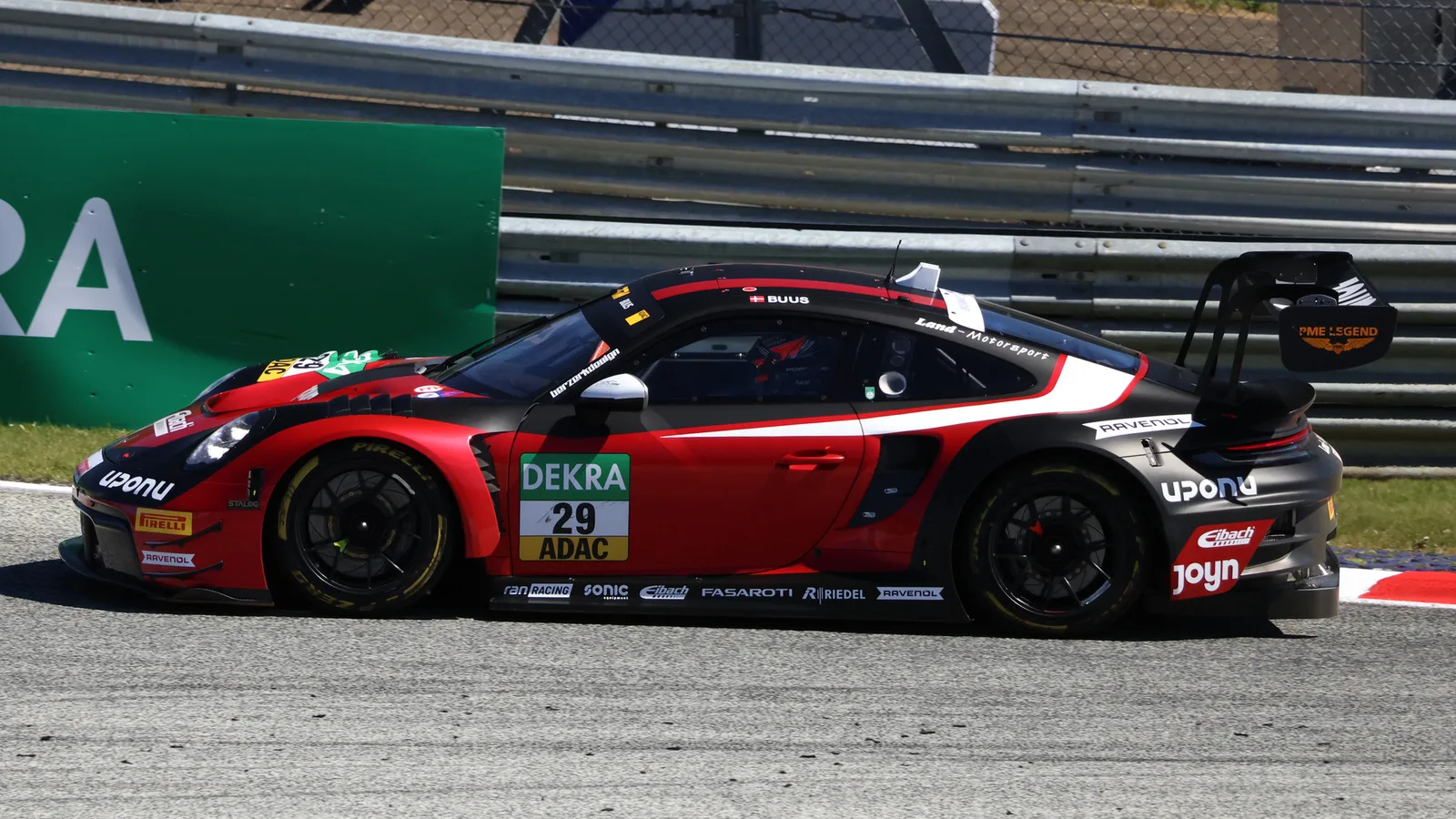 Архивен кадър на Porsche 911 GT3 R №29 на Бастиан Буус от Land-Motorsport на пистата „Шпилберг“ през 2026 г.; снимката е отпреди цветовете на Ню Инглънд Пейтриътс за финала в Хокенхайм. Lukas Raich / Wikimedia Commons, CC BY-SA 4.0; изрязана до 16:9, производното изображение е под CC BY-SA 4.0. Оригинал: https://commons.wikimedia.org/wiki/File:DTM_2026_Spielberg_Nr._29_Buus.jpg ; лиценз: https://creativecommons.org/licenses/by-sa/4.0/