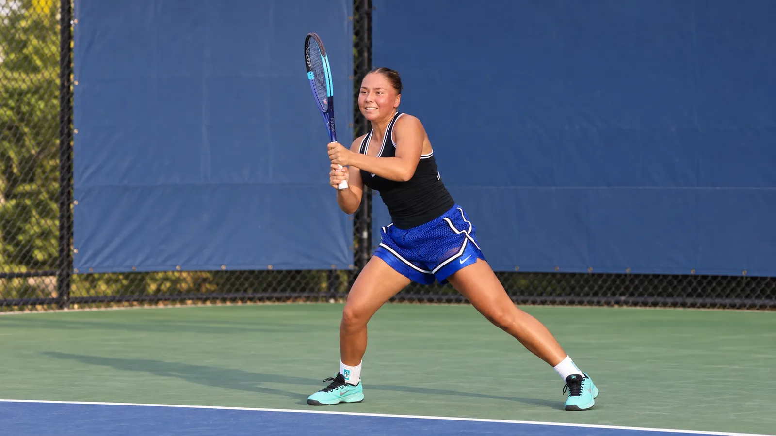 София Костулас на тенис корта в квалификациите на US Open 2026 — архивна редакционна адаптация по снимка на Hameltion, не от мача в Цзиншан. CC BY-SA 4.0: https://creativecommons.org/licenses/by-sa/4.0/; оригинал: https://commons.wikimedia.org/wiki/File:Sofia_Costoulas_(2026_US_Open)_01.jpg; разширена 16:9 композиция чрез AI редакция.