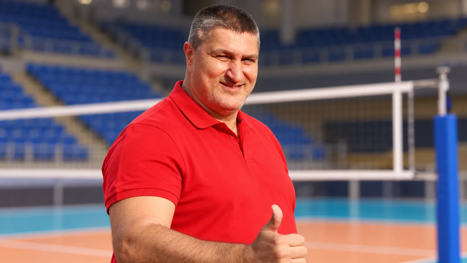 Редакционна илюстрация по архивна снимка от 2018 г. на Любомир Ганев в контекст на волейболна зала; не е кадър от Софийския маратон или бъдещия дом на волейбола. Biser Todorov / Wikimedia Commons, CC BY 4.0. Източник: https://commons.wikimedia.org/wiki/File:Lubo_Ganev_in_2018.jpg ; лиценз: https://creativecommons.org/licenses/by/4.0/ ; адаптирано изображение.