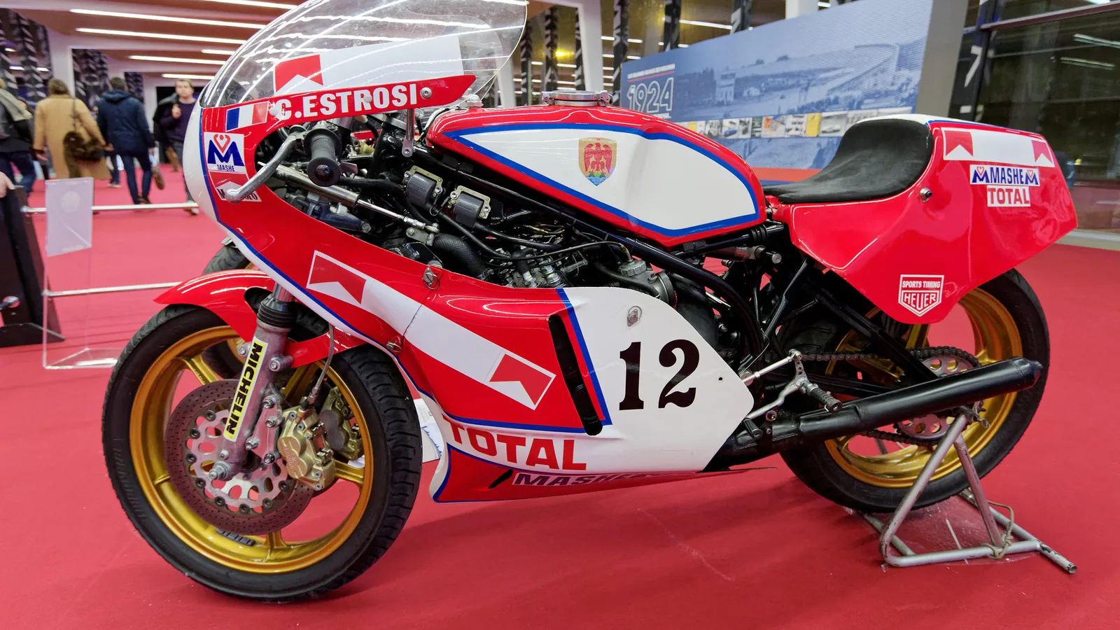 Архивна снимка на Yamaha TZ 750 OW31 от 1977 г., пилотирана от Кристиан Естрози, изложена на Rétromobile 2018; същият модел, но НЕ мотоциклетът на Джони Чекото от търга на Bonhams. Thesupermat / Wikimedia Commons, CC BY-SA 4.0; изрязана до 16:9, производната версия остава под CC BY-SA 4.0. Оригинал: https://commons.wikimedia.org/wiki/File:R%C3%A9tromobile_2018_-_Yamaha_750_OW31_-_1977_-_001.jpg ; лиценз: https://creativecommons.org/licenses/by-sa/4.0/