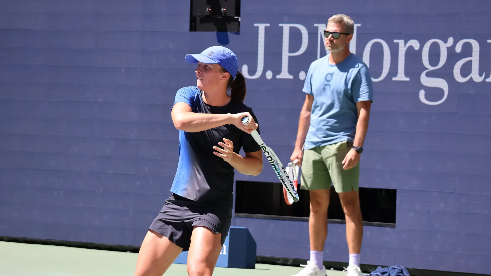 Архив: Ига Швьонтек на тренировка преди US Open, 23 август 2023 г.; не е кадър от Токио или контузията през 2026 г. Hameltion / Wikimedia Commons, CC BY-SA 4.0. Оригинал: https://commons.wikimedia.org/wiki/File:Iga_%C5%9Awi%C4%85tek_(2023_US_Open)_16.jpg ; лиценз: https://creativecommons.org/licenses/by-sa/4.0/ ; изрязано и оразмерено до 16:9, адаптация под същия лиценз.