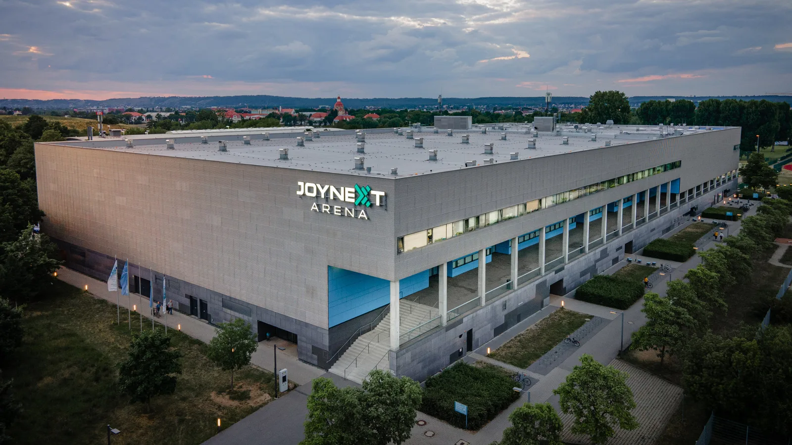Архивна въздушна снимка на JOYNEXT Arena в Дрезден от 8 юни 2022 г.; не е кадър от евакуацията или мача с Вайден. Hallenmanagement JOYNEXT Arena / Wikimedia Commons, CC BY-SA 4.0; изрязана до 16:9, производното изображение е под CC BY-SA 4.0. Оригинал: https://commons.wikimedia.org/wiki/File:JOYNEXT_Arena.jpg ; лиценз: https://creativecommons.org/licenses/by-sa/4.0/