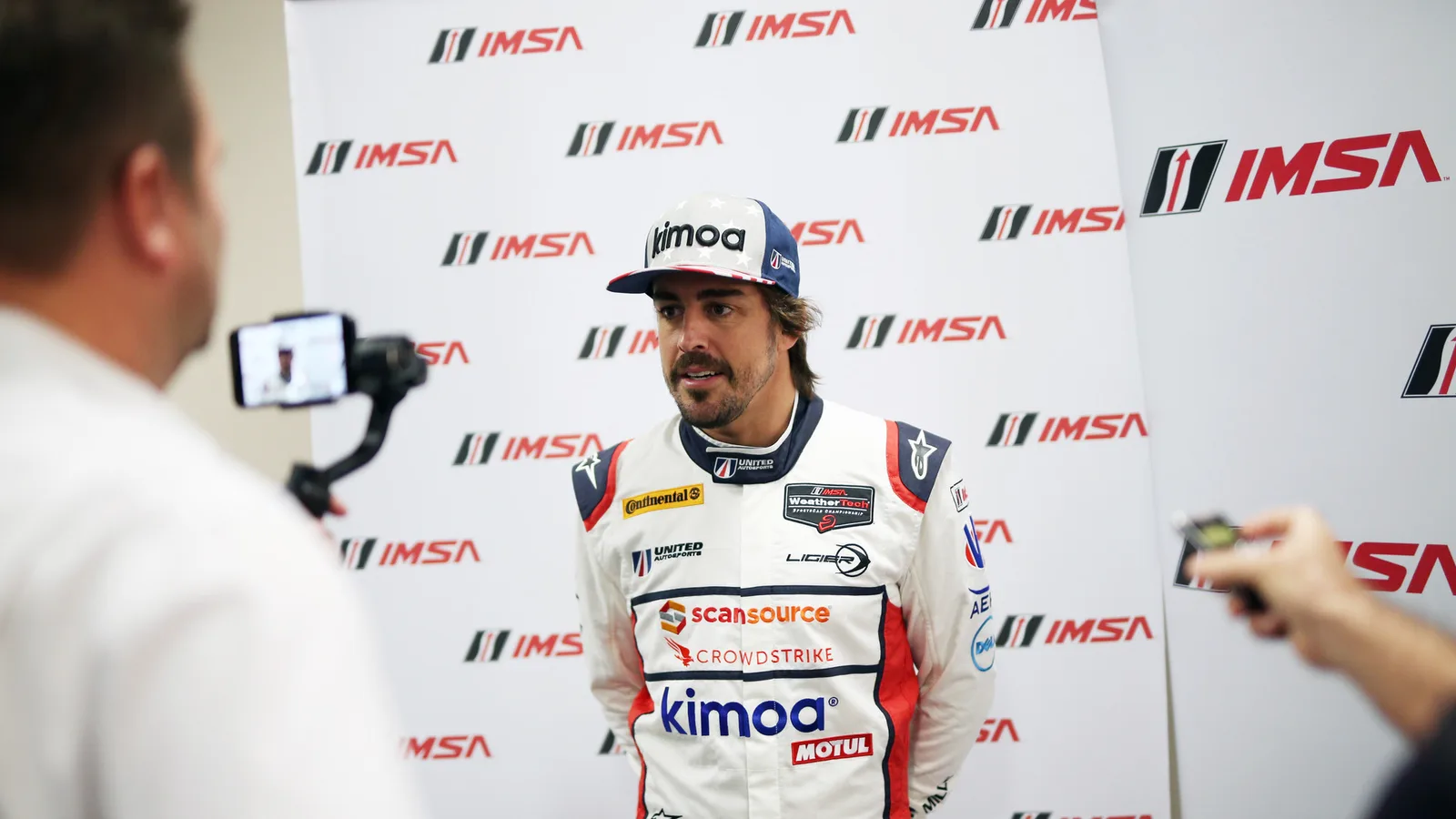Фернандо Алонсо на медийно събитие на United Autosports през 2018 г. — архивна снимка, не от рали „Дакар“ и не от сезон 2027. United Autosports / Wikimedia Commons, CC BY-SA 2.0; изрязана до 16:9. Оригинал: https://commons.wikimedia.org/wiki/File:Alonso--004_(39518578711).jpg ; лиценз: https://creativecommons.org/licenses/by-sa/2.0/