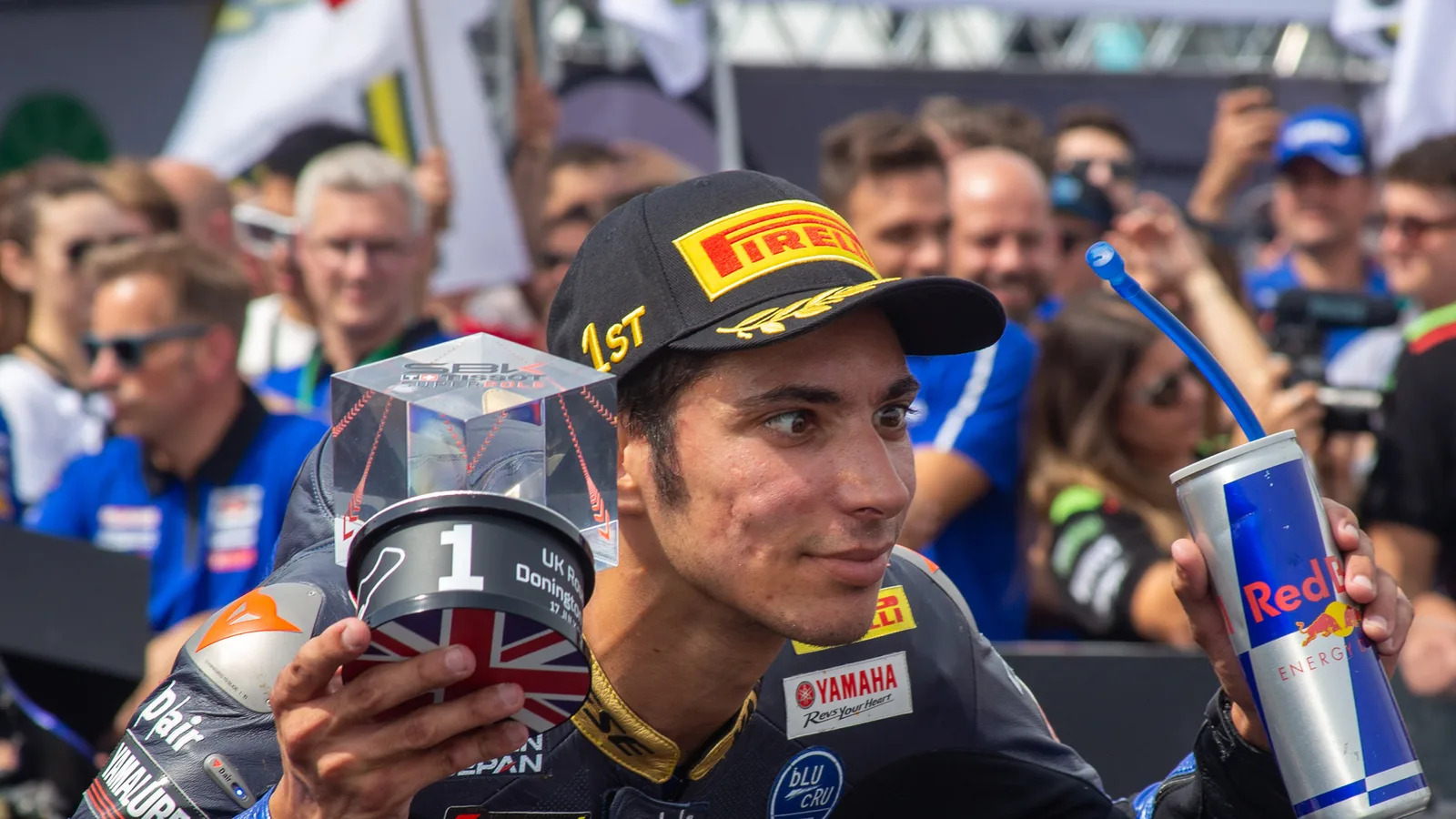Архив: Топрак Разгатлъоглу в парк ферме на World Superbike в Донингтън, 17 юли 2022 г.; не е кадър от MotoGP 2026 или контузията. Jared Earle / Wikimedia Commons, CC BY-SA 4.0. Изрязано и оразмерено до 16:9; производното остава под същия лиценз. https://commons.wikimedia.org/wiki/File:Toprak_Razgatlioglu,_2022.jpg ; https://creativecommons.org/licenses/by-sa/4.0/