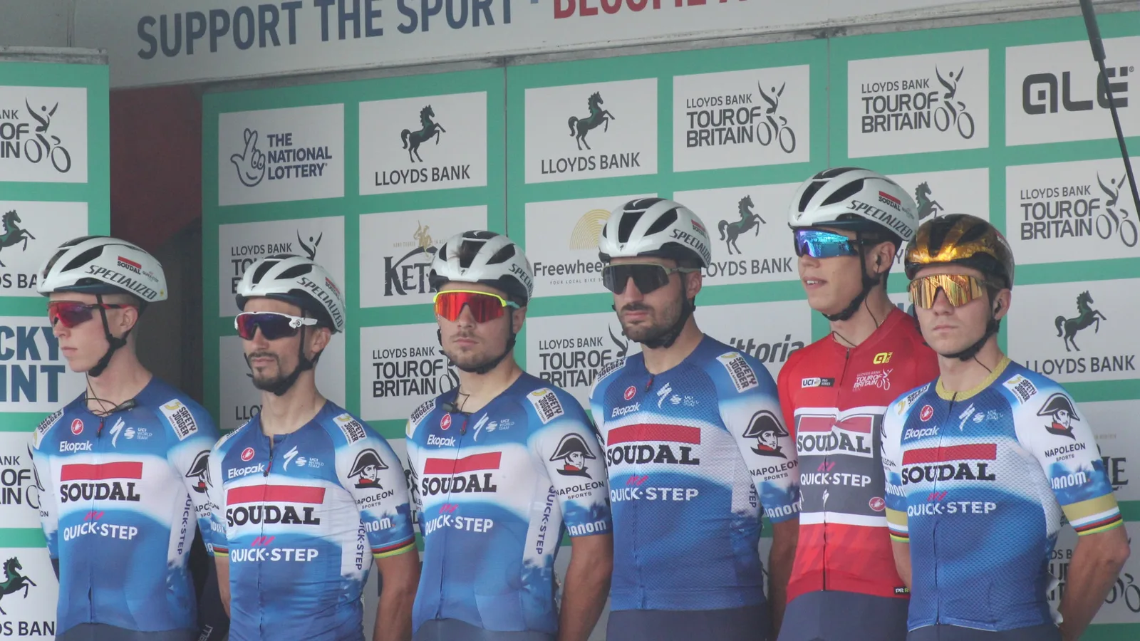 Архив: Soudal Quick-Step преди четвъртия етап на Обиколката на Великобритания през 2024 г., с каски Specialized; не е кадър от раздялата през 2026 г. Geof Sheppard / Wikimedia Commons, CC BY-SA 4.0. Изрязано до 16:9; адаптацията е под същия лиценз. Оригинал: https://commons.wikimedia.org/wiki/File:2024_ToB_stage_4_-_Team_Soudal_Quick-Step.JPG ; лиценз: https://creativecommons.org/licenses/by-sa/4.0/