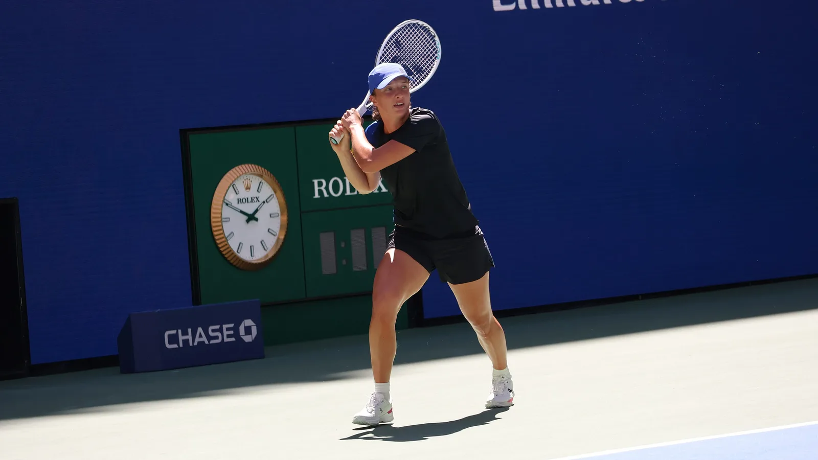 Архив: Ига Швьонтек на тренировка преди US Open през 2023 г.; не е кадър от Ухан или сезон 2026. Hameltion / Wikimedia Commons, CC BY-SA 4.0; оригинал: https://commons.wikimedia.org/wiki/File:Iga_%C5%9Awi%C4%85tek_(2023_US_Open)_45.jpg ; лиценз: https://creativecommons.org/licenses/by-sa/4.0/ ; изрязано до 16:9, адаптация под CC BY-SA 4.0.