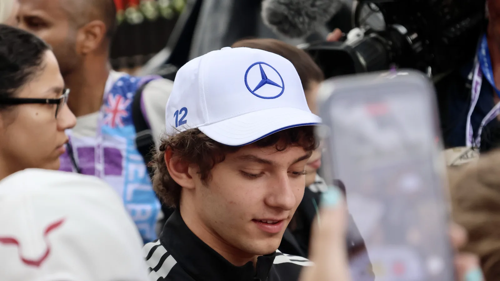 Кими Антонели с шапка на Mercedes сред фенове в Мелбърн през март 2026 г. — архивен кадър, не от състезанието в Малайзия. Yu Chu Chin / Wikimedia Commons, CC BY-SA 4.0; изрязана до 16:9. Оригинал: https://commons.wikimedia.org/wiki/File:Kimi_Antonelli_at_the_Melbourne_Walk_during_the_2026_Australian_Grand_Prix_(028A7933).jpg ; лиценз: https://creativecommons.org/licenses/by-sa/4.0/